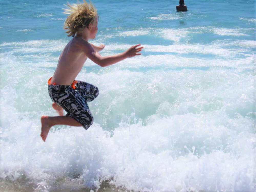 um-rapaz-salta-para-as-ondas